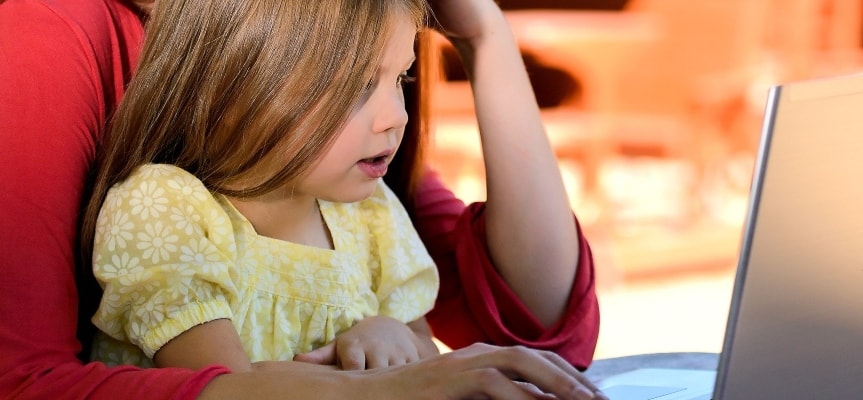 A mother and her daughter sitting at the computer looking for online jobs for moms